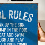 a hand holding a blue sign that says pool rules