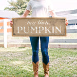 a woman holding a sign that says big time, pumpkin