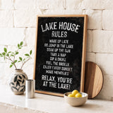 A blackboard sign with white text, a wooden board, a vase with a plant, a bowl of lemons, and a metal container on a white countertop.