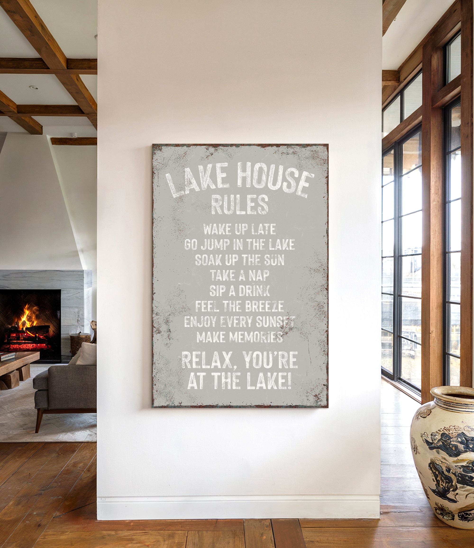 a sign that reads "LAKESHOUSE RULES" hanging on a wall in a room with a fireplace and a large window.
