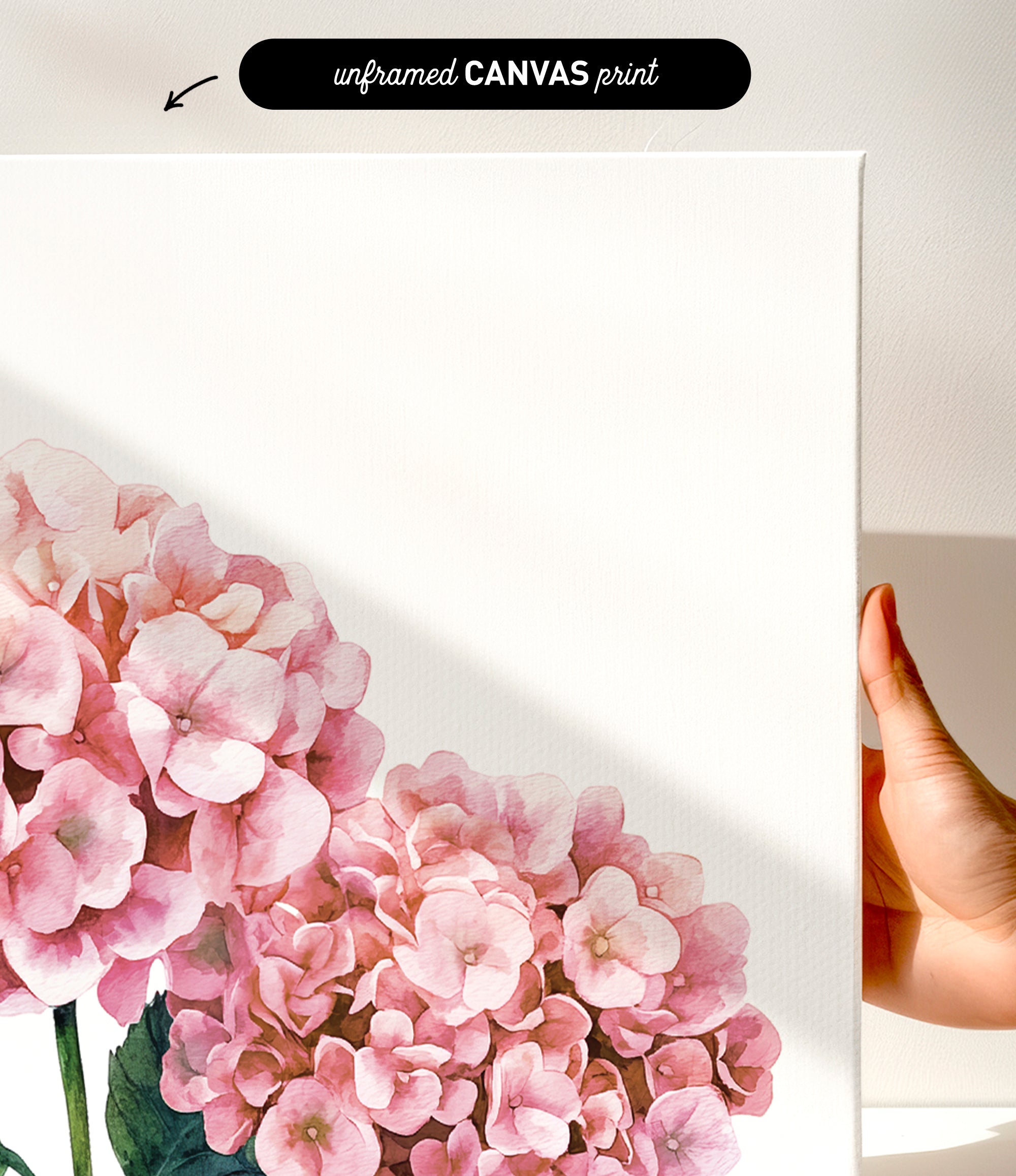a hand holding a white canvas print of a floral design, with a focus on pink hydrangea flowers.