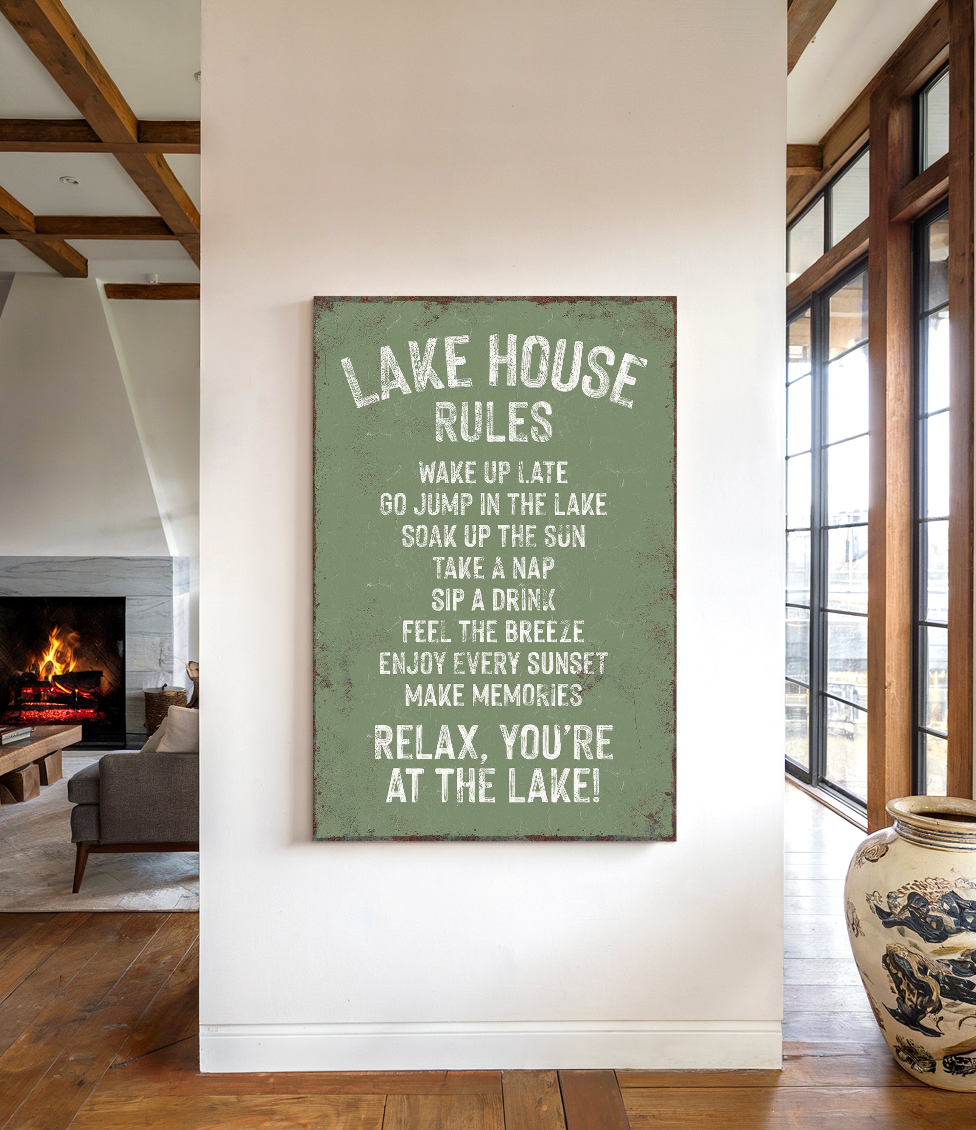 a sign that reads "LAKESHOUSE RULES" hanging on a wall in a room with a fireplace and a vase.