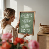 A woman is holding a framed sign with a list of rules for the Lake House, including guidelines for visitors to follow.