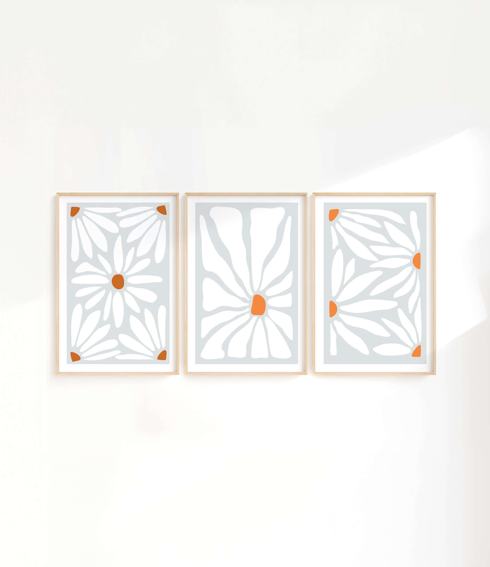three white and orange art pieces hanging on a wall