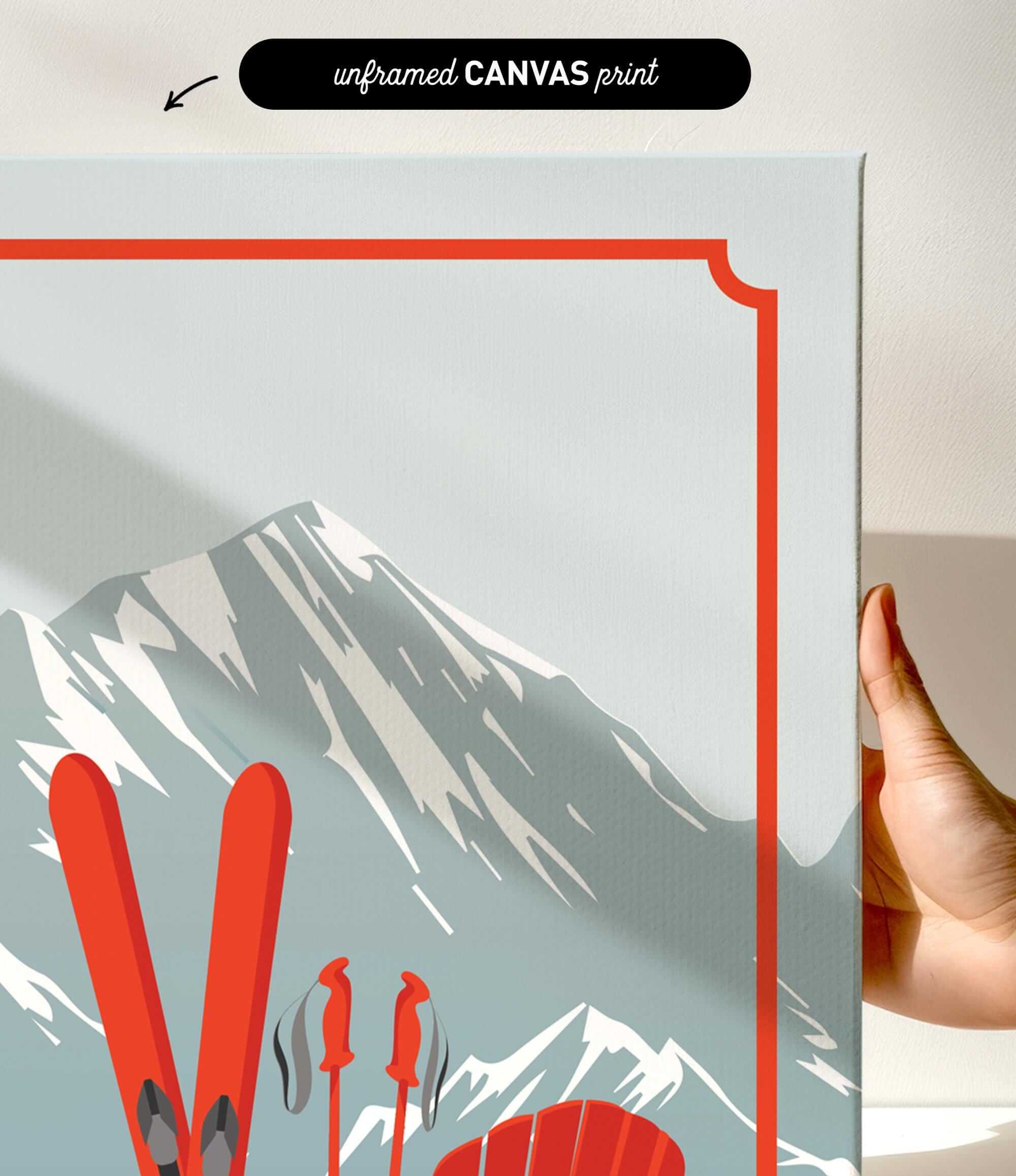 a hand holding a framed print of a mountain landscape with skis and ski poles.