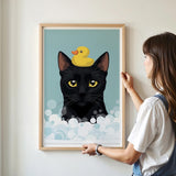 A woman is hanging a framed picture of a black cat with a yellow rubber duck on its head.