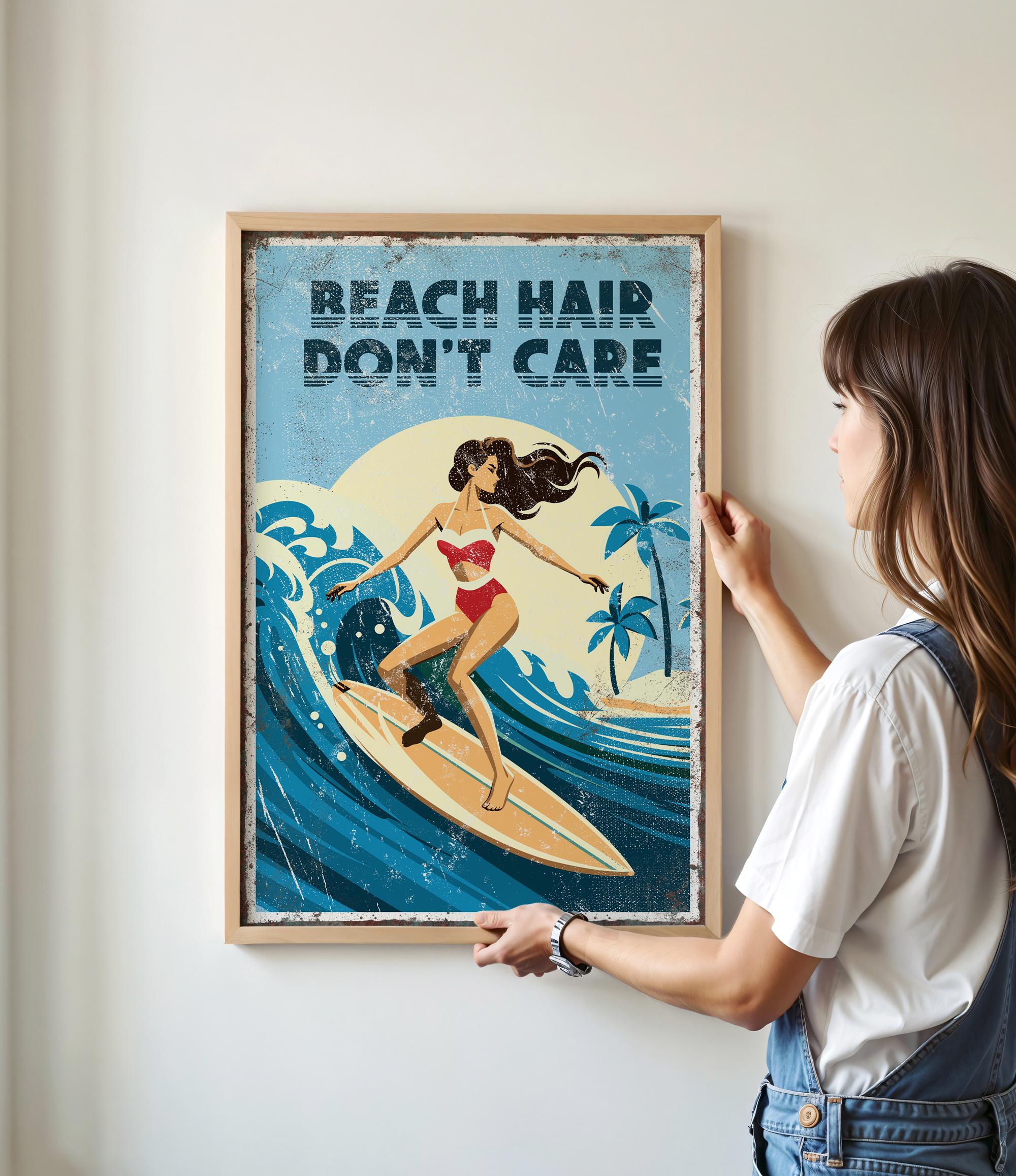 A woman is hanging a framed poster on a wall that features an illustration of a woman surfing on a wave.