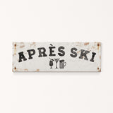 A weathered sign with the text "APRÈS SKI" and icons of a beer mug and a martini glass.