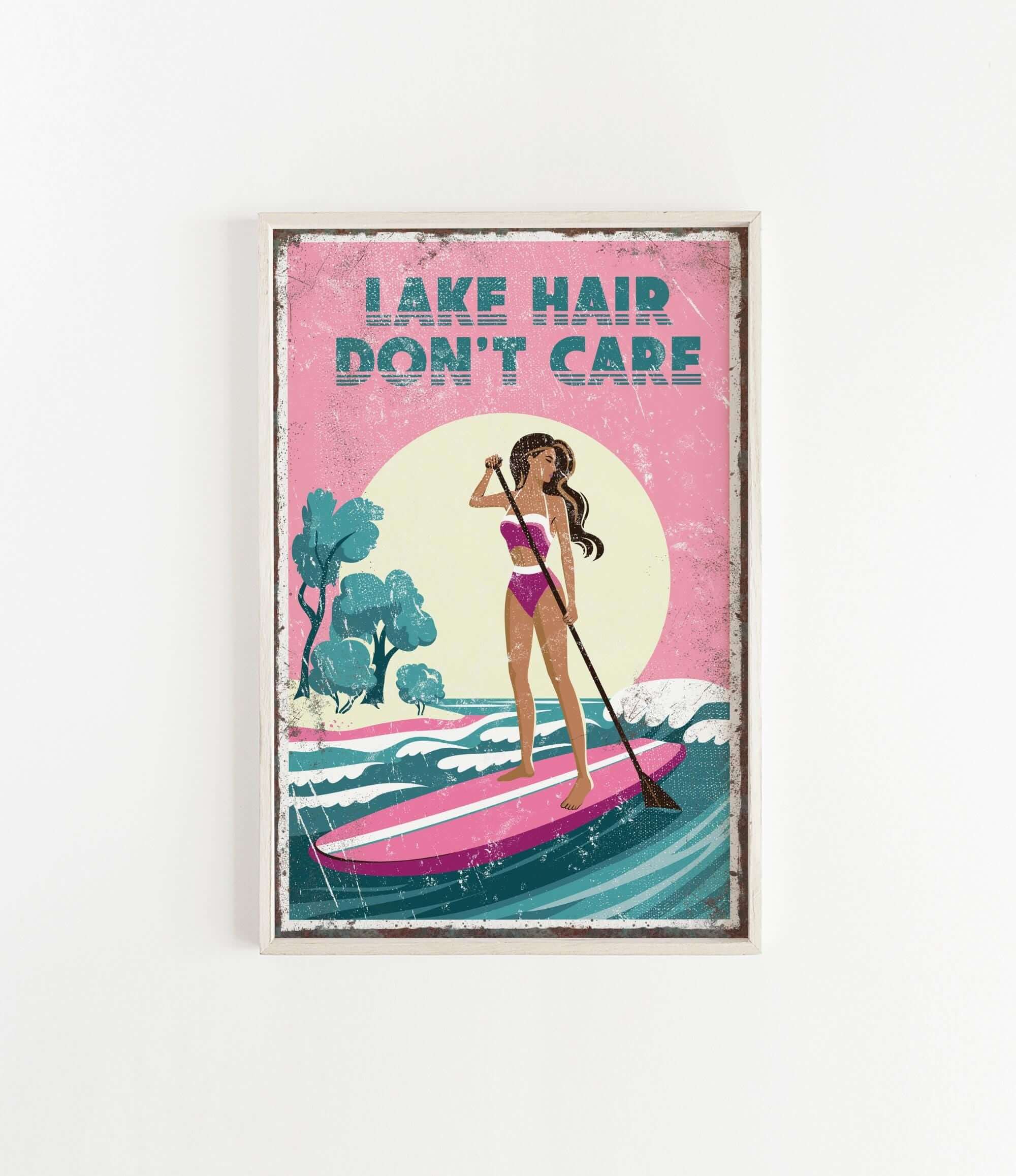 A framed poster with a woman paddleboarding on a lake, with the text "LAKESHAIR DON'T CARE" written above her.