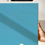 The image is a hand holding a blue canvas print with a white line running across it.