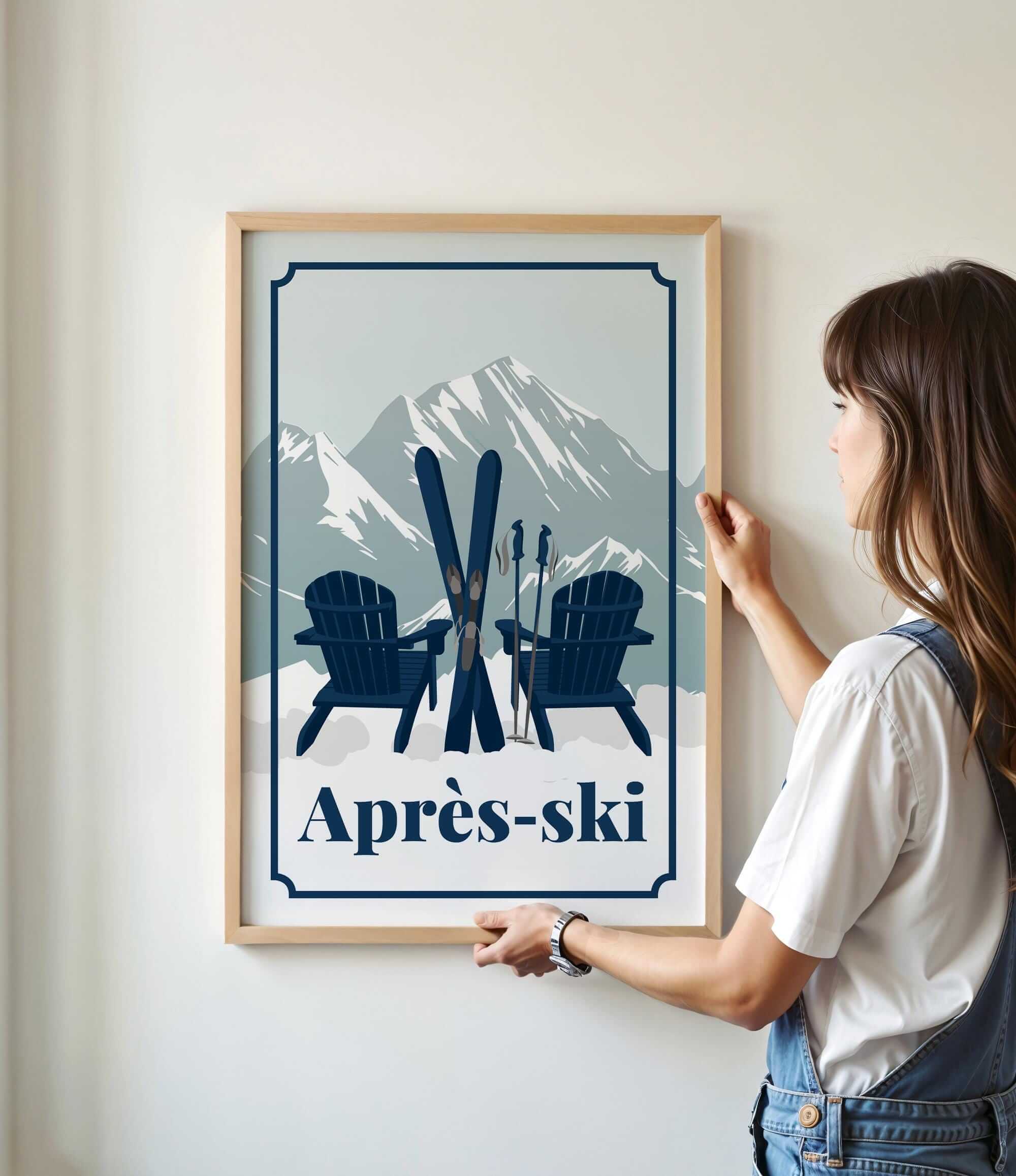 A woman is standing in front of a framed poster that features a mountain landscape with two Adirondack chairs and skis, along with the text "Apres-ski".