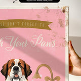 a hand holding a framed print with a dog's face and the text "Don't forget to wash your paws" on it.