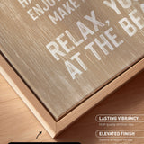 a close-up view of a wooden frame with a canvas print on it. The text on the canvas print reads "HAPPY HAVE ENJOY ME MAKE YOU MAKE AT THE BEACH". The text is in white and is located on the wooden frame.