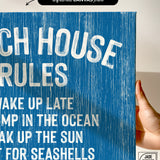 Hand holding the Beach House Rules Sign in ocean blue painted wood with white text, ideal as coastal wall art or stylish beach house décor.