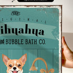 a hand holding a framed print with a dog and a sink, along with text that reads "The original bubble bath co."