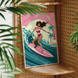 A framed illustration of a woman surfing on a pink surfboard, with palm trees and a sunset in the background.