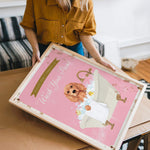 A woman is holding a framed poster with a dog in a bathtub, and the poster has a pink background with a message about washing dogs.