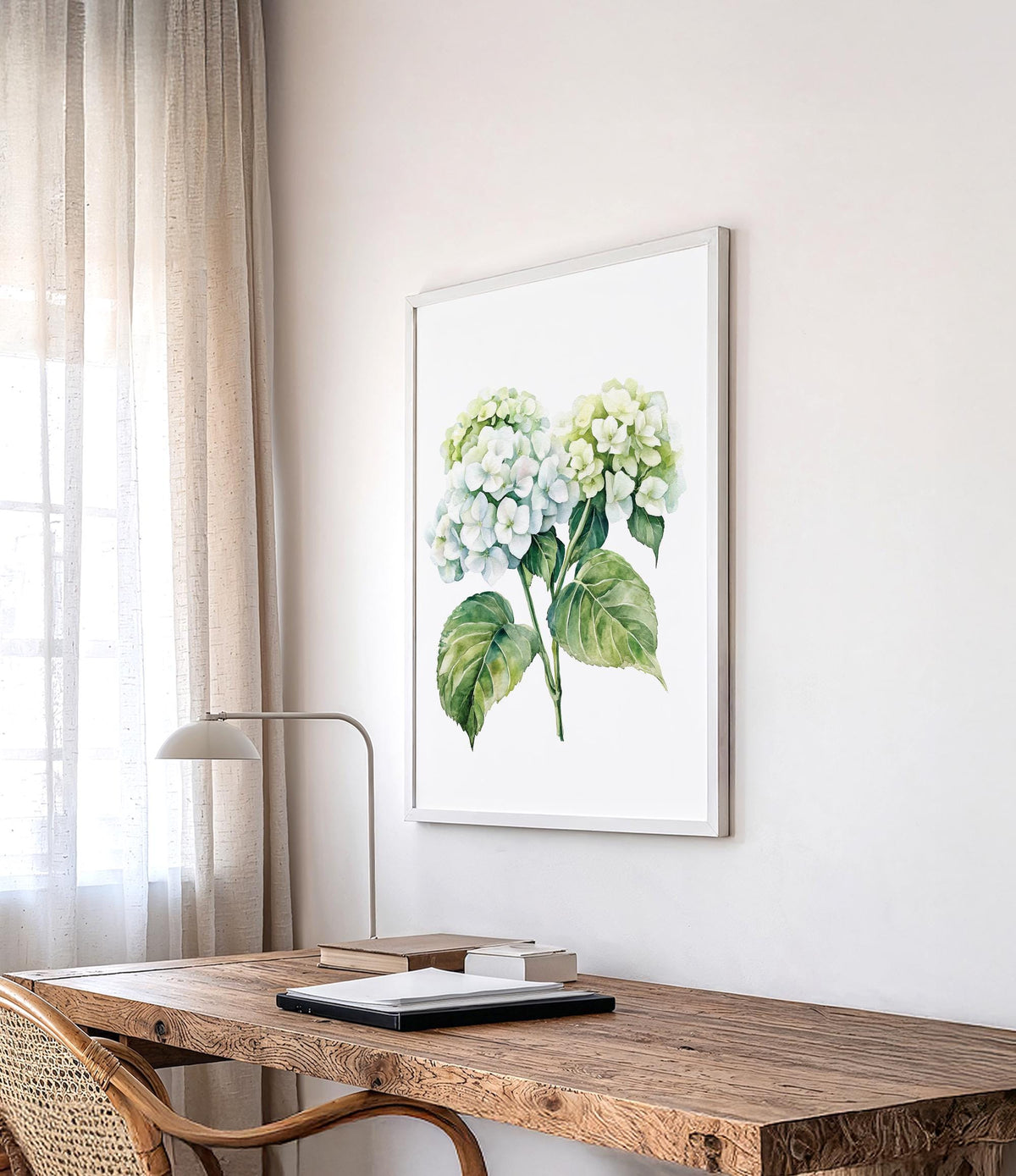 a wooden desk with a lamp, a framed watercolor painting of green hydrangeas, and a window with sheer curtains.