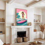 a living room with a fireplace, a large framed poster of a woman paddleboarding, and various decorative elements such as vases and a potted plant.