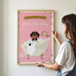 A woman is hanging a framed poster on a wall that features a dog sitting in a bathtub filled with bubbles.