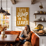 A woman sits on a red couch in a cozy kitchen, with a wooden sign above her that reads "Let's JUMP IN THE LEAVES".