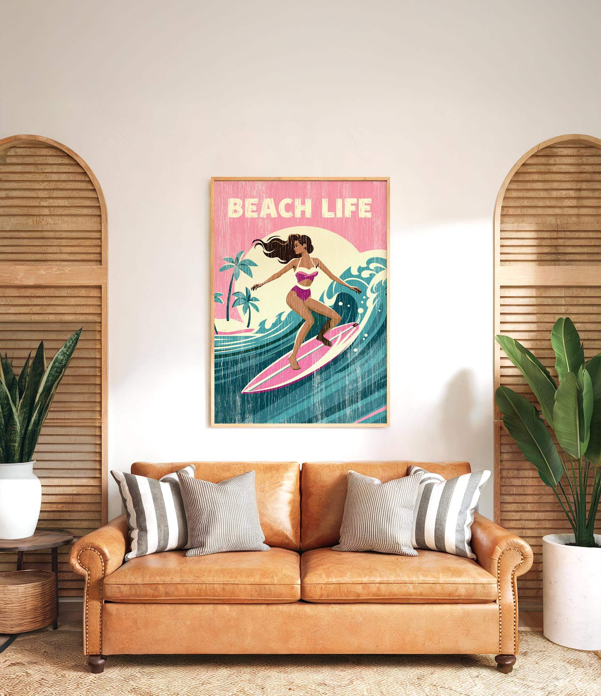 a framed poster of a woman surfing on a beach, with the text "BEACH LIFE" prominently displayed. The poster is hung on a wall above a brown leather couch, which is positioned in front of two potted plants.