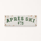 A weathered sign with the text "APRES SKI" in green letters, along with icons of a beer glass and a martini glass, indicating a location or establishment related to skiing and alcoholic beverages.