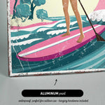 A woman is standing on a pink surfboard and holding a paddle, with a colorful landscape in the background.