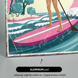 A woman is standing on a pink surfboard and holding a paddle, with a colorful landscape in the background.
