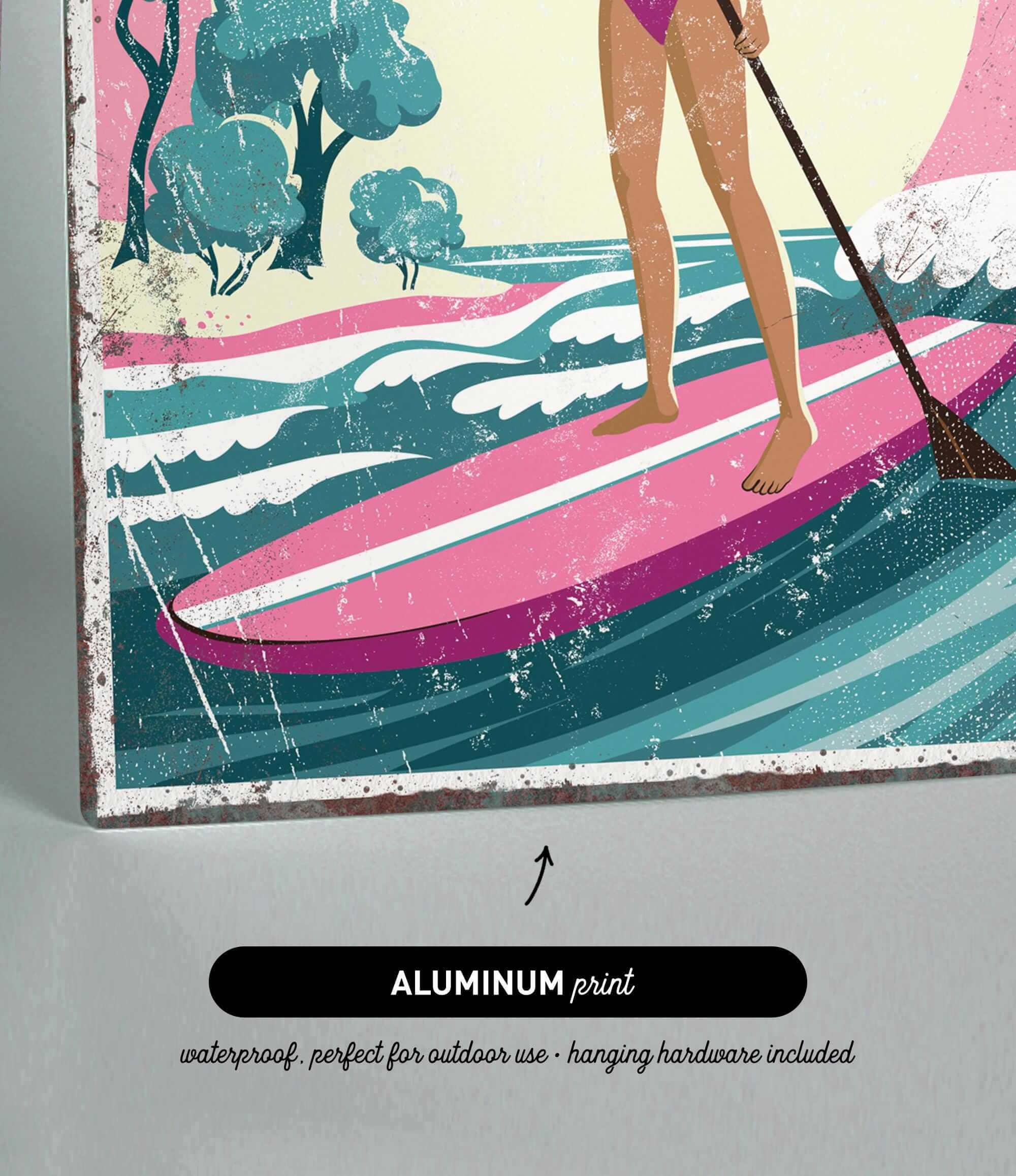 A woman is standing on a pink surfboard and holding a paddle, with a colorful landscape in the background.