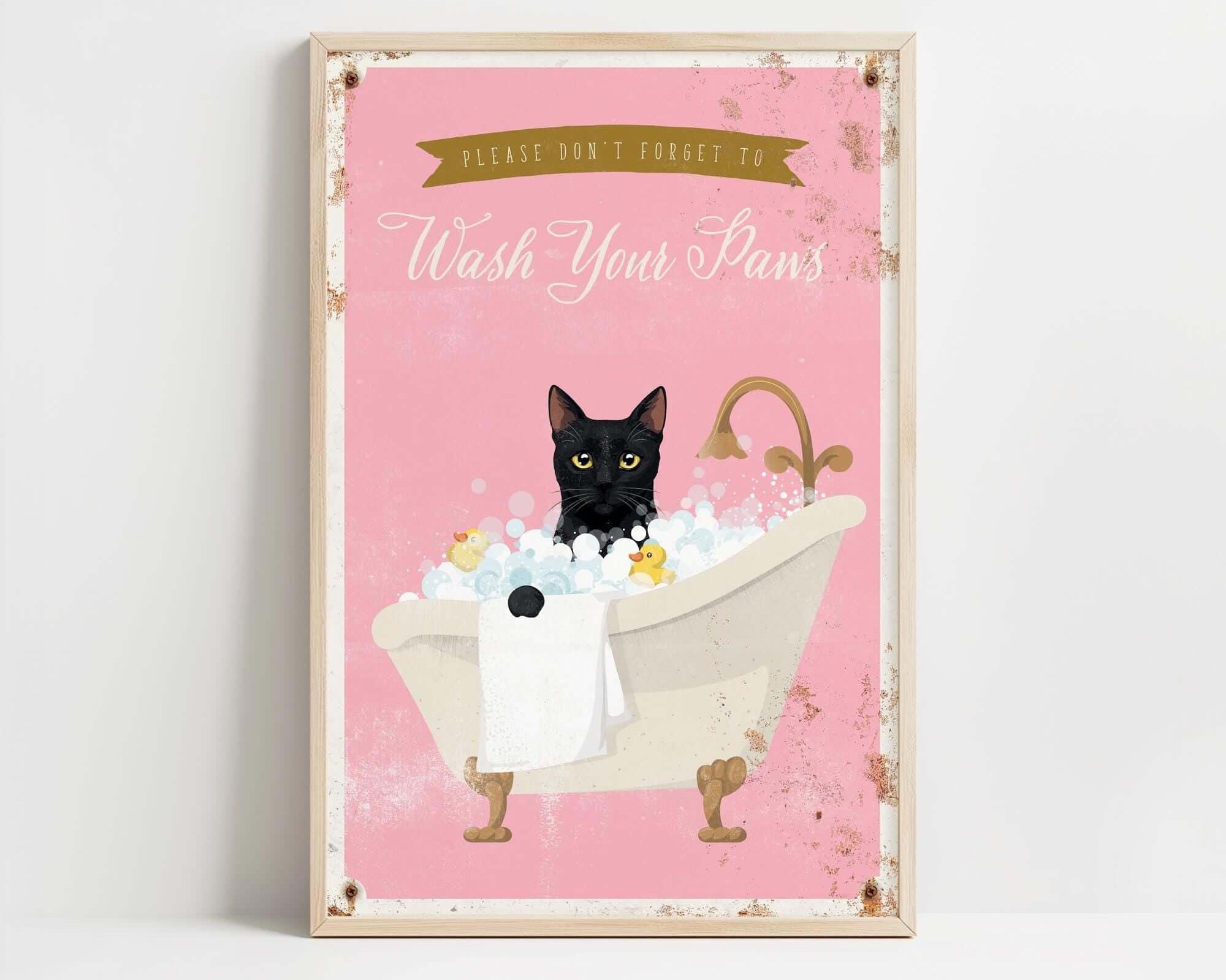 A framed poster with a black cat sitting in a bathtub filled with bubbles, accompanied by the text "Please don't forget to wash your pans".