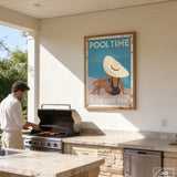 A man grilling food on a barbecue in an outdoor kitchen area with a framed poster above the grill.
