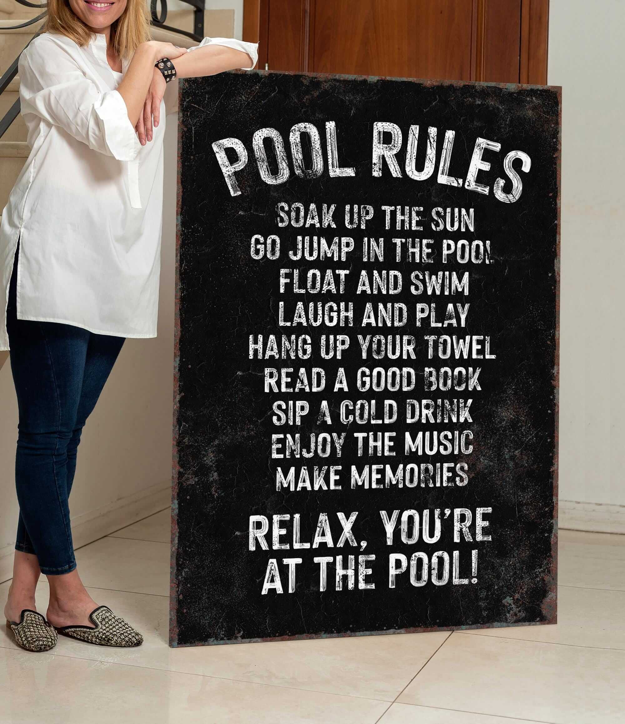 a woman standing next to a pool rules sign