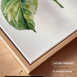 a close-up view of a watercolor painting of a green leaf on a white background. The painting is framed in a wooden frame, which adds a natural touch to the overall presentation.