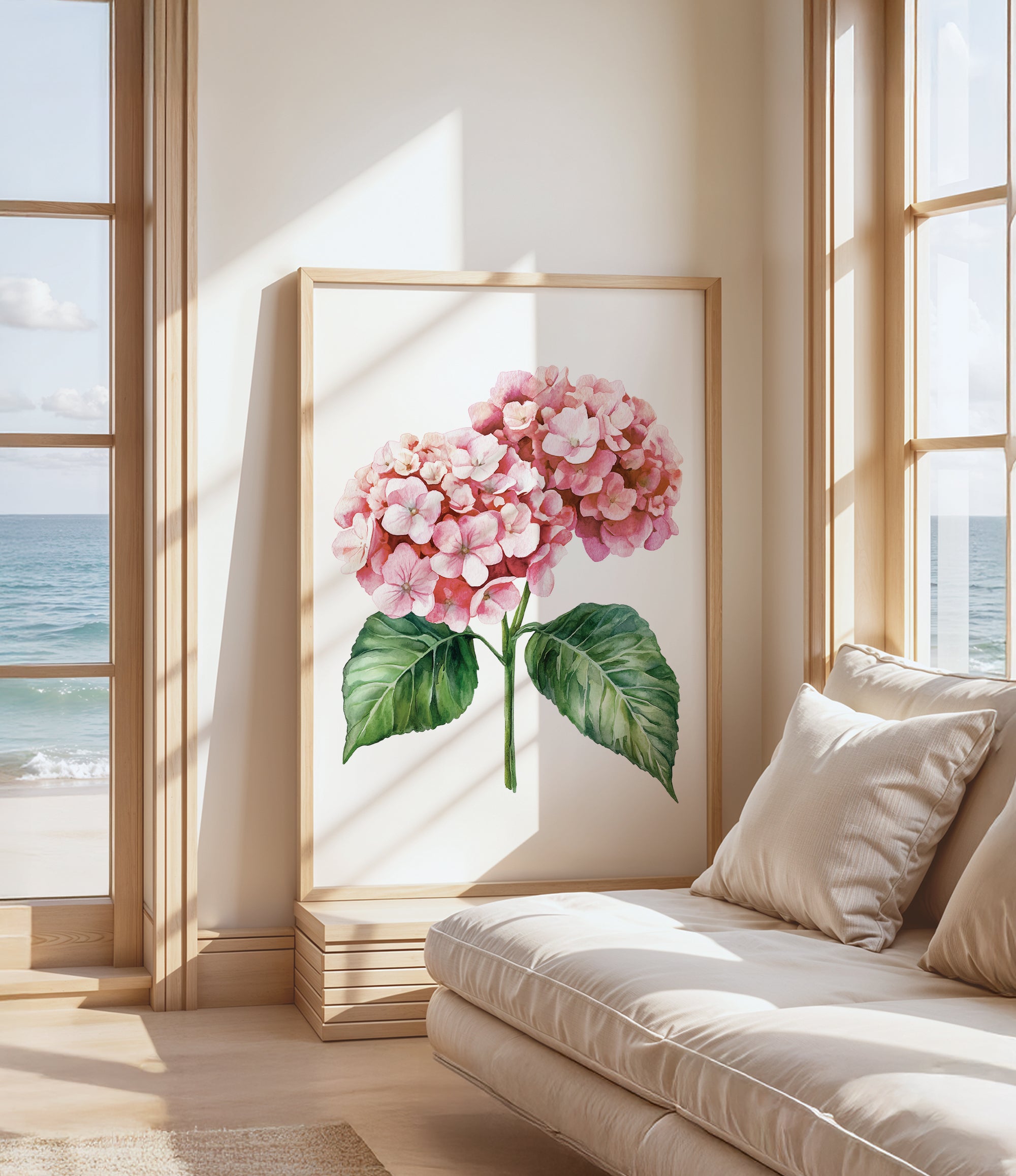 a large framed painting of a pink hydrangea flower with green leaves, placed on a wall near a window overlooking the ocean.