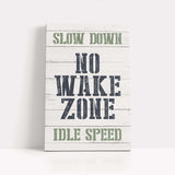 a wooden sign that says slow down no wake zone