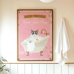 A framed poster with a cat sitting in a bathtub, surrounded by bubbles, and a towel hanging on the wall.