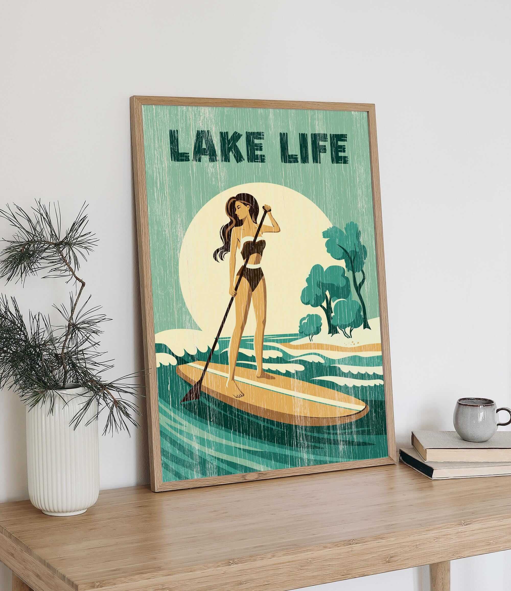 a framed poster of a woman paddleboarding on a lake, with the text "LAKELIFE" prominently displayed.