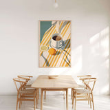 a dining room with a wooden table and four chairs, a bowl on the table, and a painting of a cup, lemon, and orange on the wall above the table.