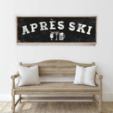 a wooden bench with two striped pillows, and above it is a framed sign with the text "APRÈS SKI" and various icons representing drinks and skiing equipment.