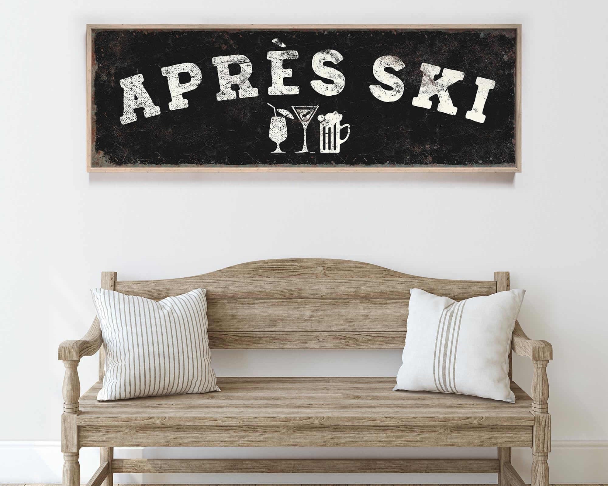a wooden bench with two striped pillows, and above it is a framed sign with the text "APRÈS SKI" and various icons representing drinks and skiing equipment.