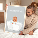 A woman is sitting on a bed holding a framed poster with a dog sitting in a bathtub filled with bubbles.