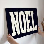 a person holding up a sign that says noel