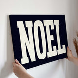 a person holding up a sign that says noel