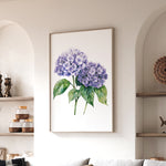 a framed watercolor painting of purple hydrangeas hanging on a wall in a living room.