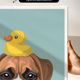 A hand is holding a framed print featuring a cartoon image of a dog with a yellow rubber duck on its head.