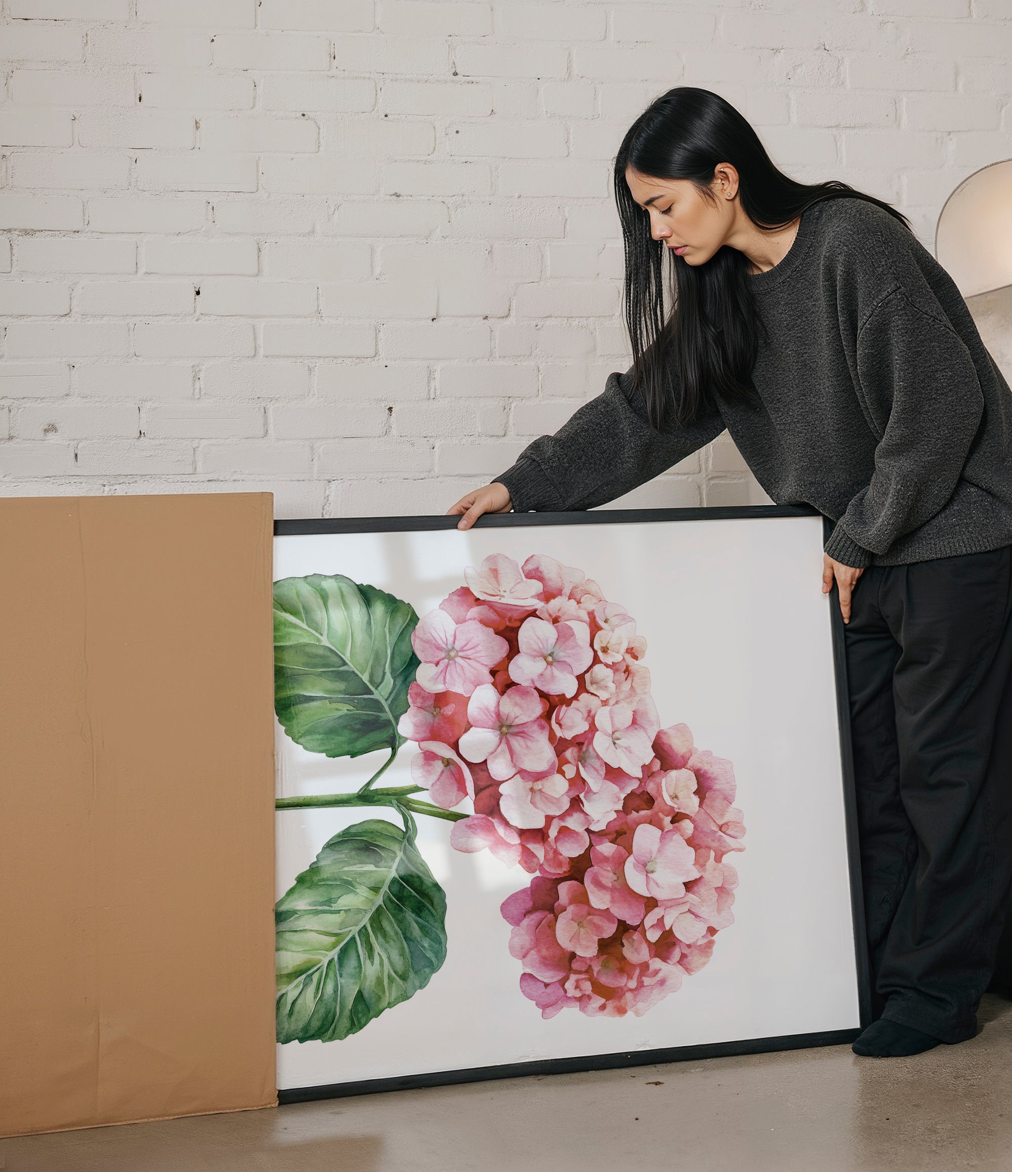 A woman is standing next to a large framed painting of a pink flower, examining it closely.