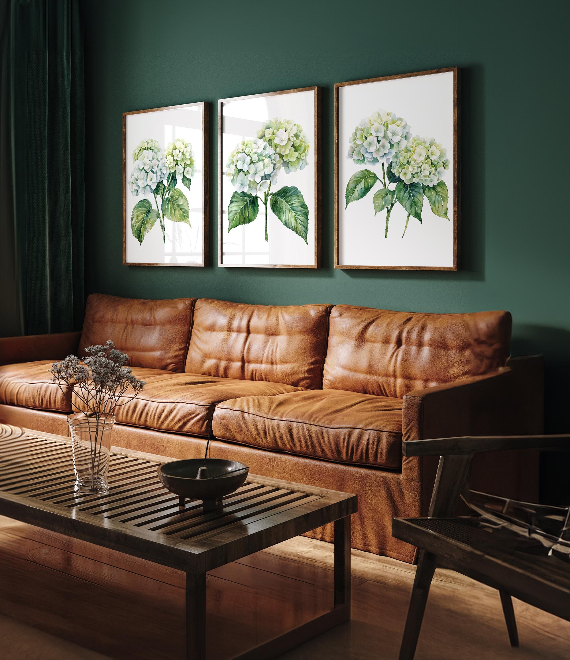 a cozy living room with a brown leather couch, a wooden coffee table, and three framed watercolor paintings of white hydrangeas hanging on the wall above the couch.