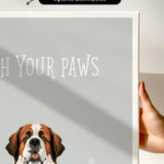 a hand holding a framed print of a dog's face, with the text "Wash Your Paws" written on the print.