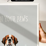 a hand holding a framed print of a dog's face, with the text "Wash Your Paws" written on the print.